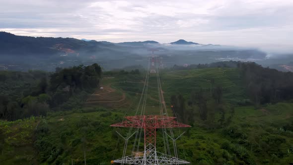 Fly over red and white electric pylon at green rural area