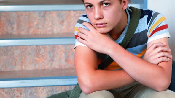 Sad schoolboy sitting alone on staircase