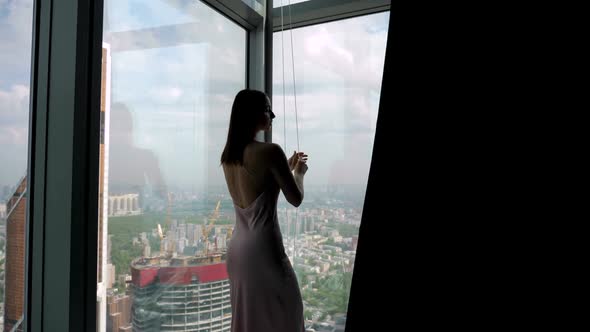 Woman Opens a Panoramic Window with a Curtain with Her Hand