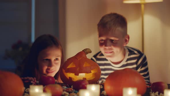 Happy Caucasian Kids Looking at Jack Lantern Standing at Table