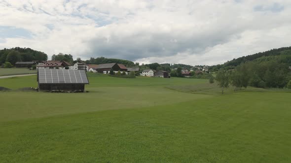 Sheep graze on a field near a barn with solar panels