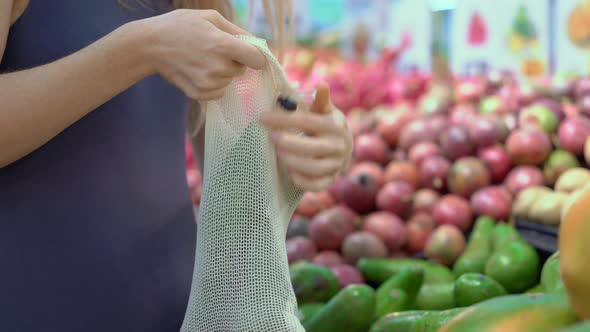 A Woman Puts Avocados in Reusable Tissue Bag in a Supermarket