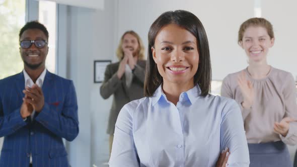 Portrait of Confident African Businesswoman and Team Applauding on Background Smiling at Camera