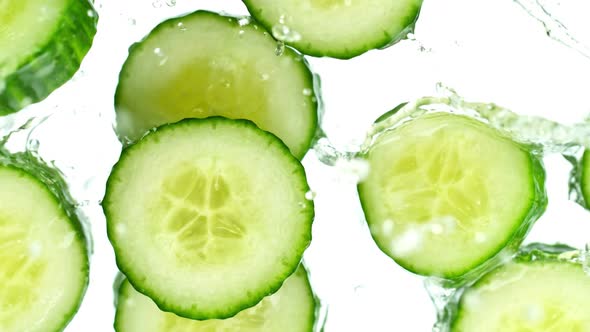 Super Slow Motion Shot of Cucumber Slices Falling Into Water on White Background at 1000Fps