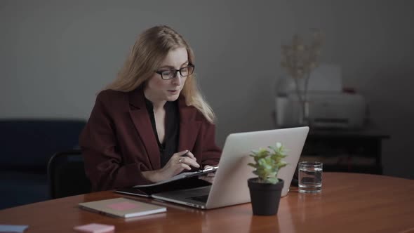 Businesswoman Making Video Call to Business Partner Using Laptop Looking at Screen Wearing Pods and