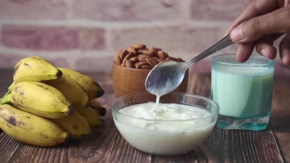 Fresh Yogurt in a Bowl  Banana  Almond Nut and Milk on Table