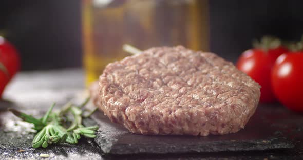 Raw Burger of Fresh Meat Rotates on a Stone Board. 