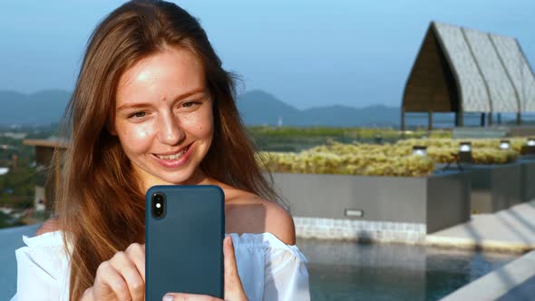 Young Smiling Woman with Smartphone Typing Message or Make Video Call