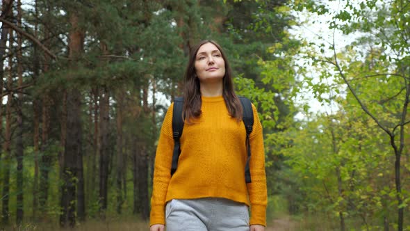 Woman Walks Along Rural Road Across Green Forest with Pines