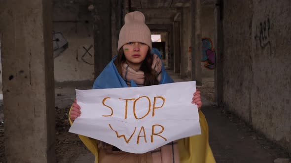 Upset Ukrainian poor girl kid refugee protesting war conflict raises banner with inscription massage