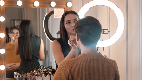 Woman Make Up Artist Applying Contour Shades on the Nose of Male Model Using a Brush