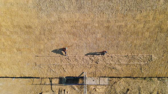 Aerial View the Roof of a Large House with Dry Straw and Hay. Workers Who Install the Roof