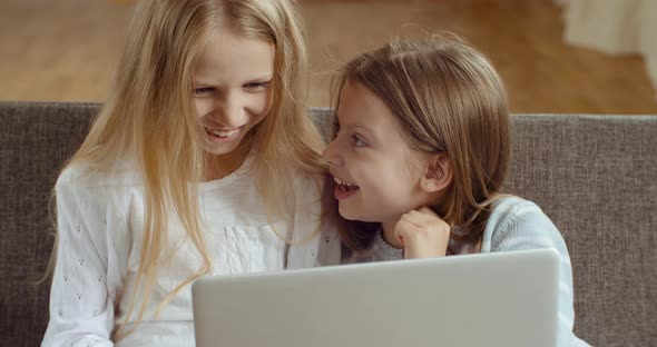 Children and Technology. Two Girls Sisters Sitting in Living Room Together Looking at Laptop Screen