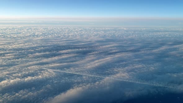 Incredible view from the cockpit of an airplane flying high above the clouds leaving a long white co