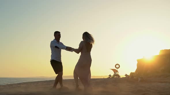 Newlyweds a Young Couple at a Romantic Meeting on the Seashore at Sunset Dancing in Slow Motion