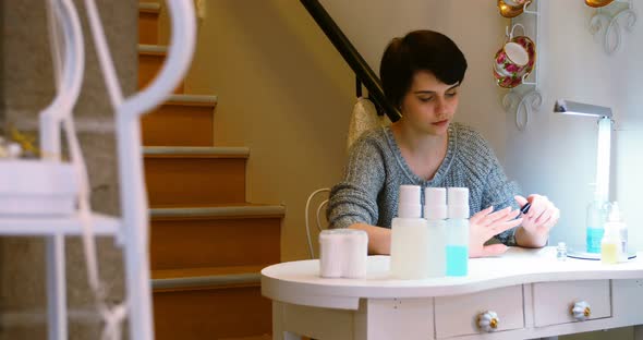 Woman applying nail polish to her finger nails