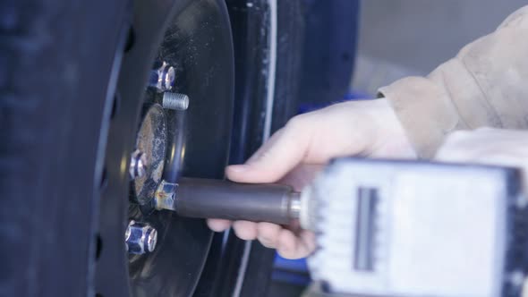 UHD A man takes the bolts off of a tire with a power drill and then res the tire