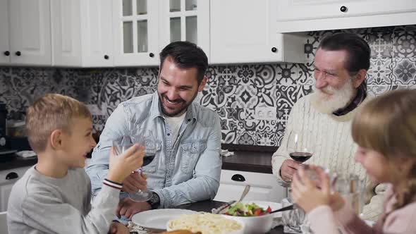 Father and Grandpa with Cute Boy and Girl Sitting at the Table on Thanksgiving Day