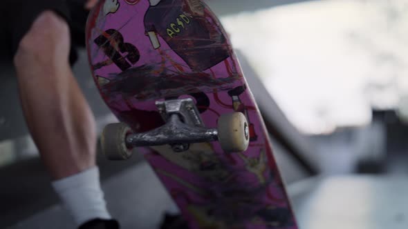 Unrecognizable Man Resting with Pink Skate Board at Urban Skate Park