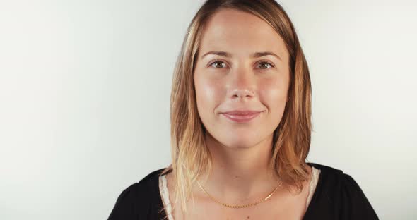 Close up of a young blond woman smiling on white studio background