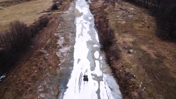 Drone shot of the forest and a country icy river in the late autumn. Late Autumn forest hills. Aeria