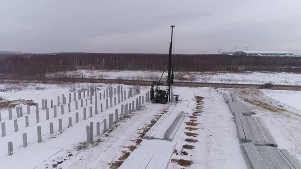 Aerial drone view of a pile bore machine drives the pile into the ground 07