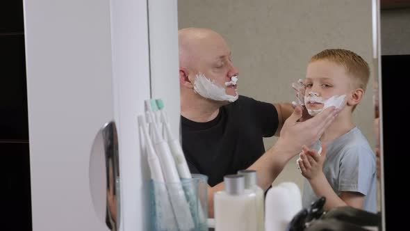 Father Showing His Little Son How to Shave He Applies Shaving Cream to His Face