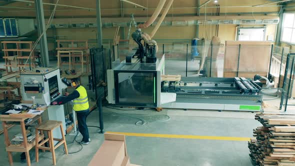 Woodworking Factory Worker Operates a Machine.