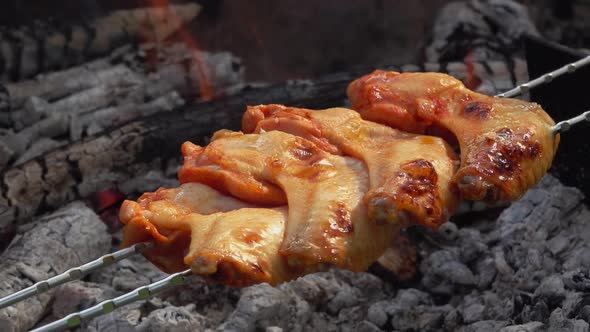 Closeup of Tasty Chicken Wings on the Skewers Are Flipped Above the Open Fire