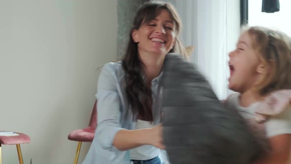 Mother Sits on the Carpet and Plays with Her Daughter the Child Runs Around