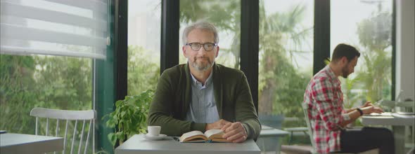 Grey-haired man sitting at table in cafe