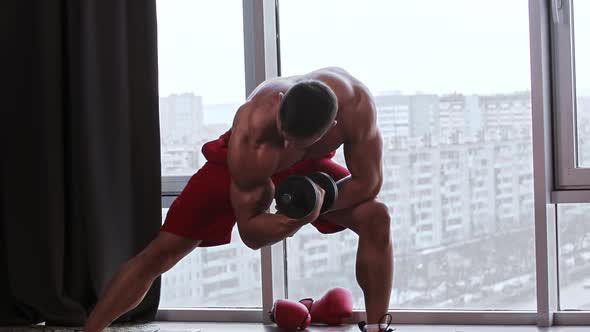 Athletic Muscular Shirtless Man Training His Hands Muscles with a Dumbbell