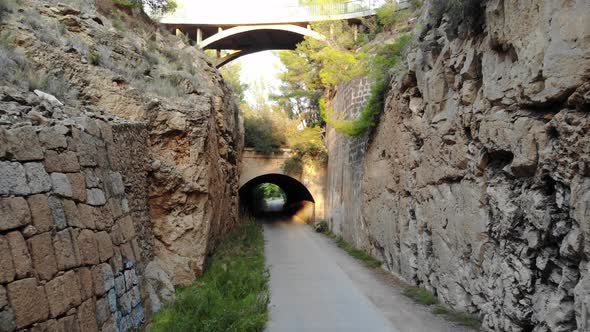 couple walking through tunnel without light surrounded by nature and beautiful cliffs with vegetatio