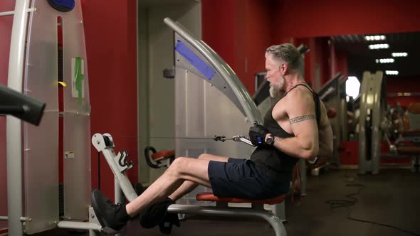 Gray-haired man doing back exercises on a training machine
