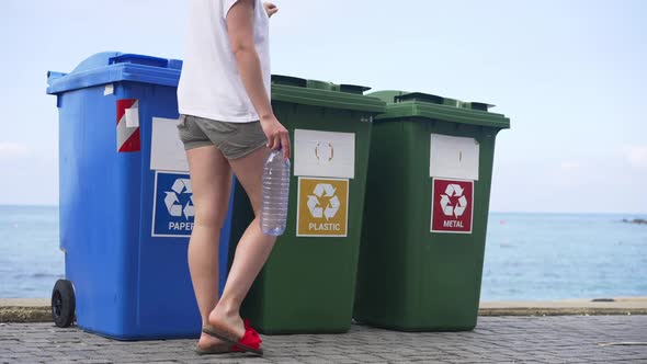 Containers for Separate Waste Collection on Sea Beach with Young Slim Caucasian Woman Passing