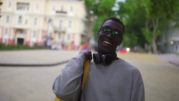 Portrait of Young African American Man in Stylish Glasses and Headphones Looking at Camera Smile