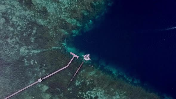 Coral reef island in Raja Ampat Indonesia with boat leaving diving pier area, Aerial top view loweri