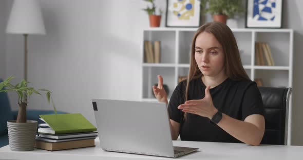 Woman Is Conducting Webinar Sitting at Home in Front of Laptop with Web Camera Talking and