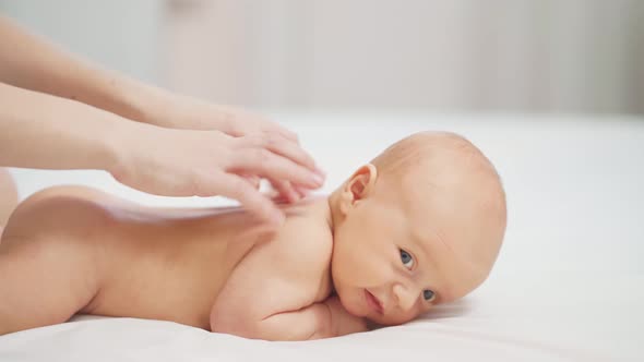 the Baby Lies on His Tummy on a White Sheet