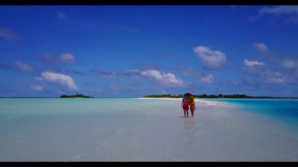 Romantic couple sunbathe on paradise tourist beach holiday by blue ocean with white sandy background