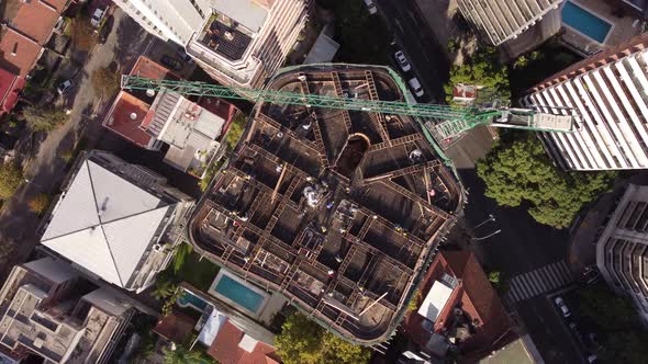 Aerial straight down shot showing industrial construction site on rooftop of extreme high skyscraper