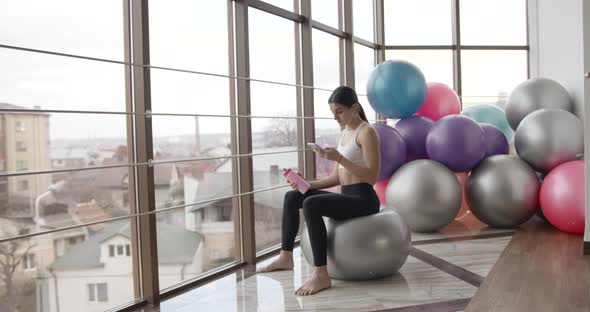 Young Beautiful Woman Using Smartphone at Gym