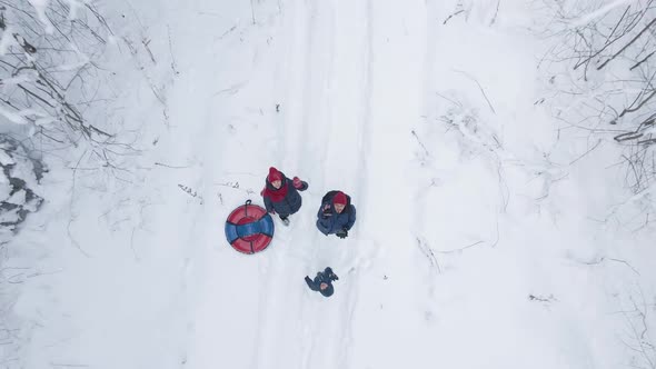 Family of Three Stands in a Snow Covered Forest in Winter