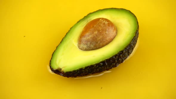 Rotating segment of a ripe and juicy avocado on an orange background. Slow motion.