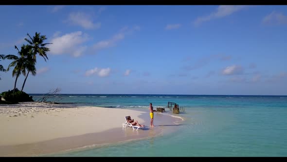 Man and woman suntan on tranquil lagoon beach wildlife by shallow ocean with white sandy background 