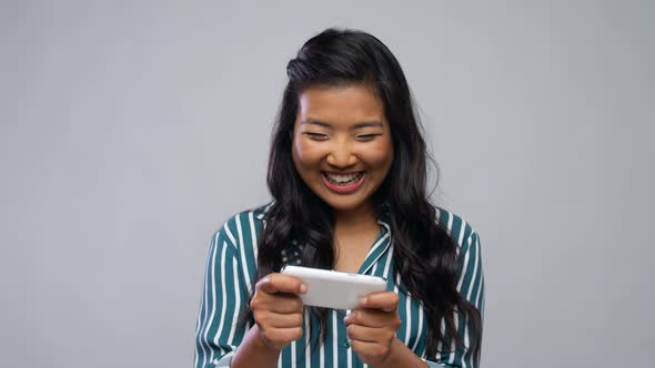 Happy Asian Woman Playing Game on Smartphone