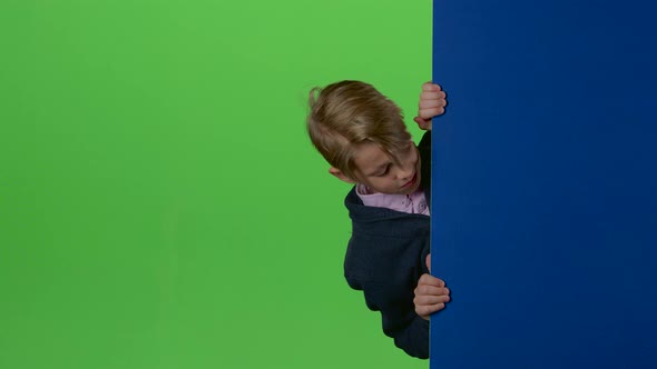 Child Boy Peeps Out From the Wall on a Green Screen