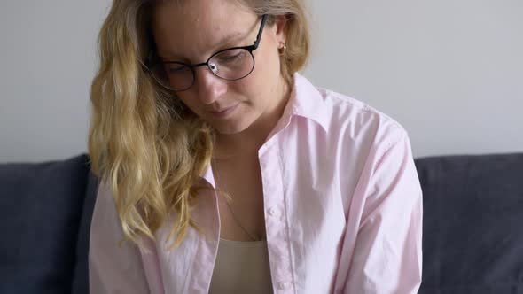 Closeup Beautiful Blonde Woman Sitting at Home on the Couch Works Remotely Via the Internet alt