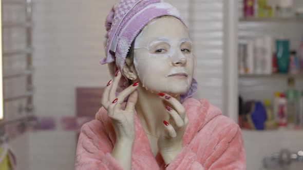 Woman Applying Cosmetic Face Mask in Bathroom. Skincare Spa. Facial Mask