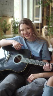 Two Lgbt Girls are Sitting in the Lining Room on the Sofa Playing Guitar and Singing Songs Slow